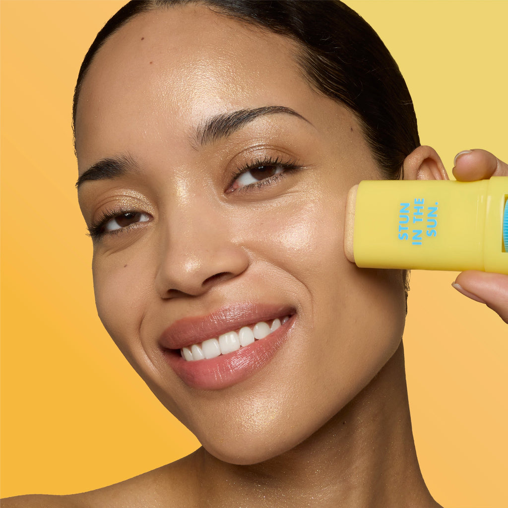 Close-up of a woman applying Invisi-Stick Glitz SPF 50 broad-spectrum sunscreen - Medium skin tone