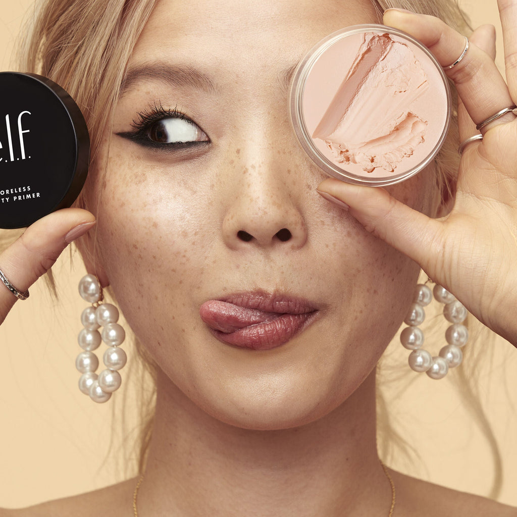 Woman wearing and holding Poreless Putty Primer by e.l.f.